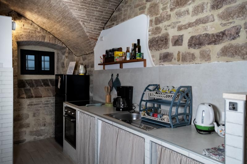 A fully equipped kitchen combining rustic stone architecture with modern appliances.