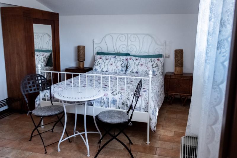 Romantic atmosphere in the Peonia Room with a white wrought-iron bed and bistro seating.