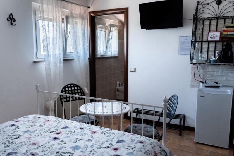 Romantic atmosphere in the Peonia Room with a white wrought-iron bed and bistro seating.