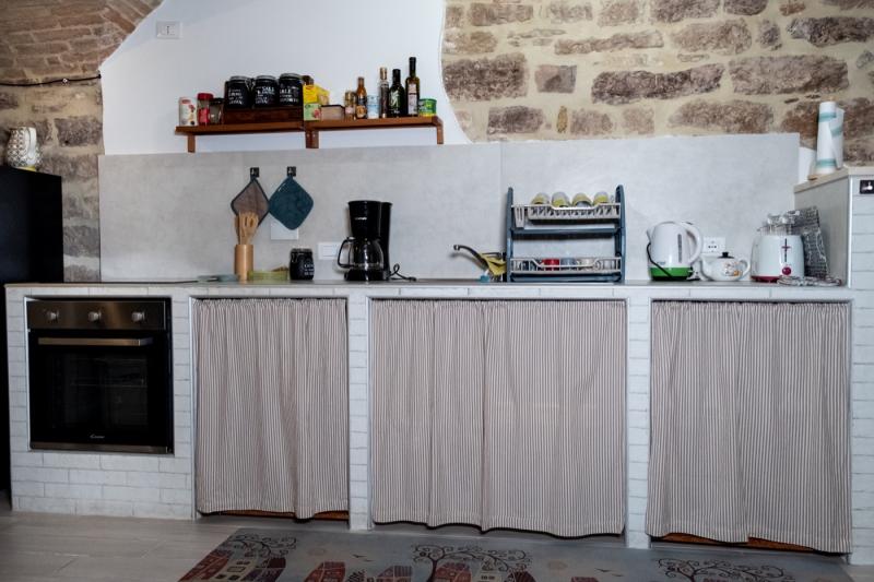 A fully equipped kitchen combining rustic stone architecture with modern appliances.