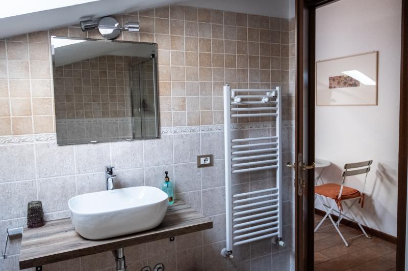 Bright attic private bathroom with modern fixtures and a wooden washbasin console. Bright attic private bathroom with modern fixtures and a wooden washbasin console.