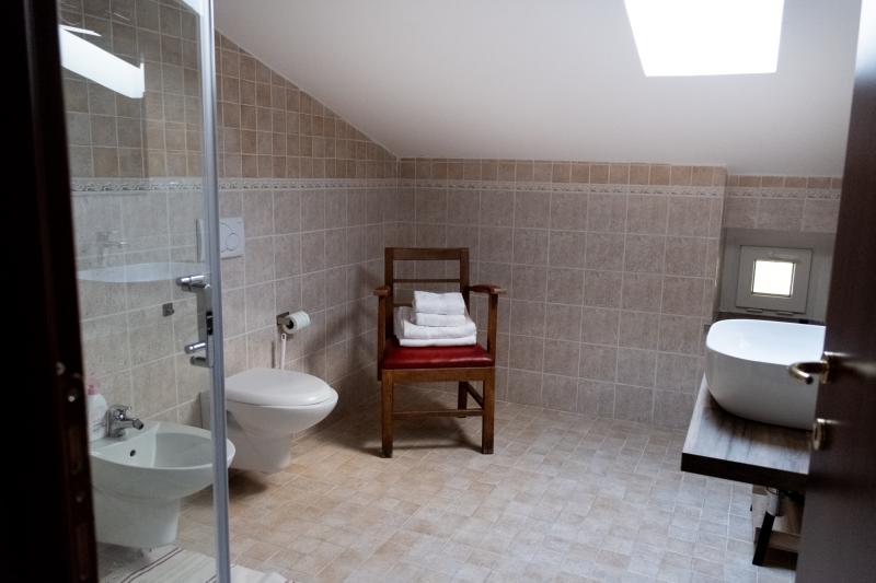Bright attic private bathroom with modern fixtures and a wooden washbasin console. Bright attic private bathroom with modern fixtures and a wooden washbasin console.