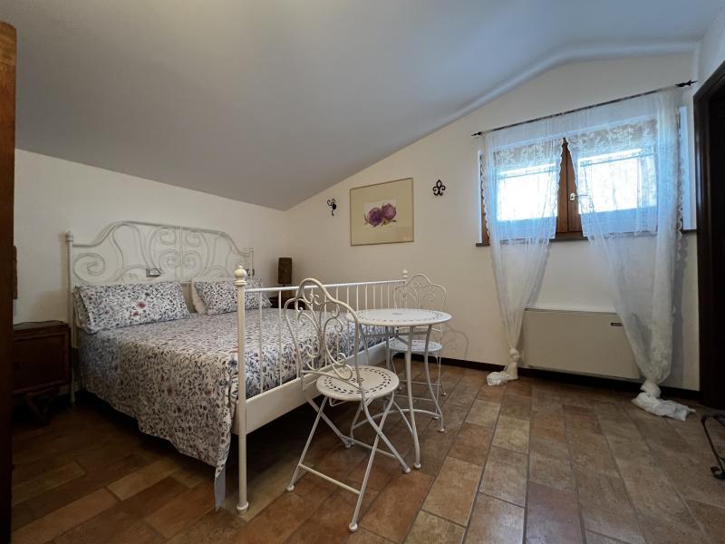 Romantic atmosphere in the Peonia Room with a white wrought-iron bed and bistro seating.